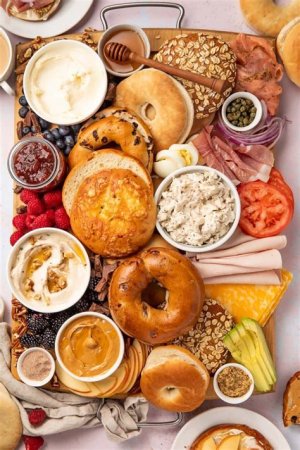 A wedding bagel bar with a variety of bagels, cream cheese spreads, hummus, and toppings like smoked salmon, cucumbers, and tomatoes for guests to create their own bagel sandwiches.
