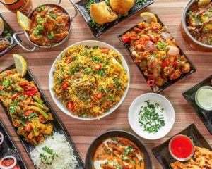 A curry station at a wedding with a variety of curries like chicken, vegetable, and lentil curry, served with rice and naan bread for guests to enjoy.