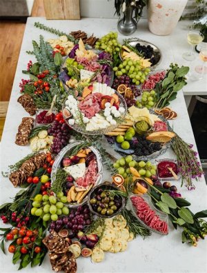 A wedding grazing table featuring a variety of cheeses, crackers, fruits, vegetables, nuts, and dips for guests to enjoy.